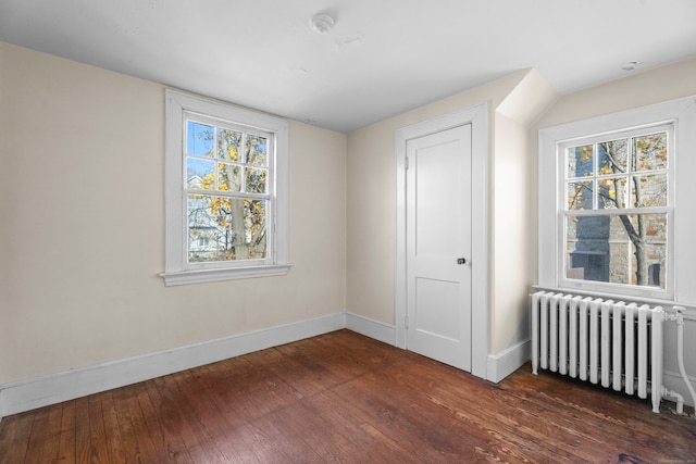 unfurnished bedroom featuring dark hardwood / wood-style flooring, radiator, and multiple windows