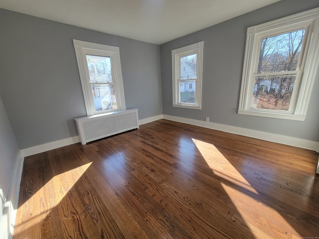 spare room with radiator heating unit, dark hardwood / wood-style floors, and a healthy amount of sunlight