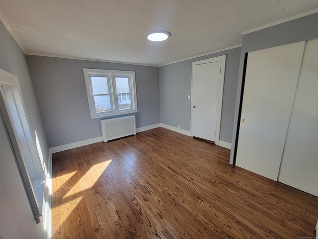 unfurnished bedroom featuring radiator heating unit, dark wood-type flooring, and ornamental molding