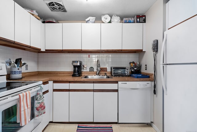 kitchen featuring sink, a textured ceiling, white appliances, decorative backsplash, and white cabinets