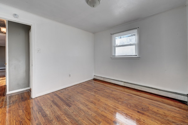 empty room featuring hardwood / wood-style floors and a baseboard radiator