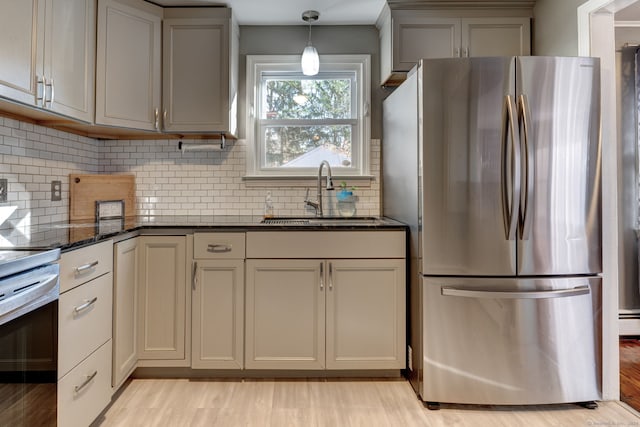 kitchen featuring decorative backsplash, stainless steel fridge, dark stone counters, sink, and decorative light fixtures