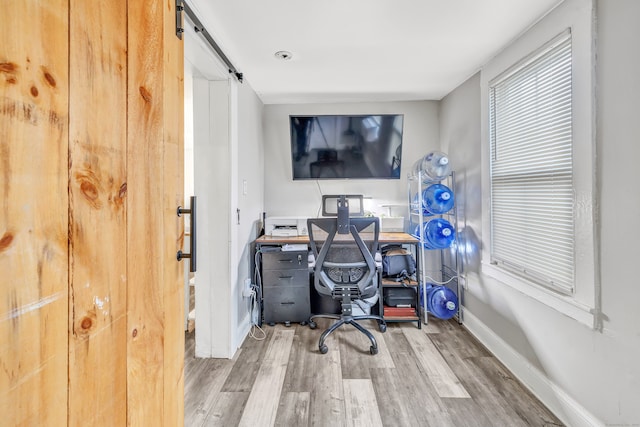 home office with a barn door and wood-type flooring