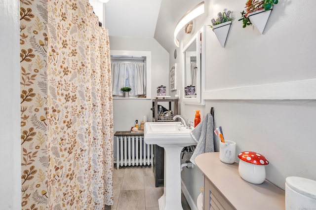 bathroom featuring lofted ceiling, sink, and radiator