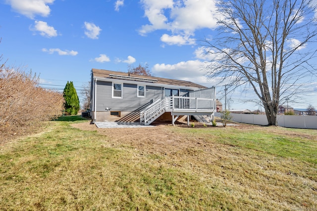 rear view of house with a lawn and a wooden deck