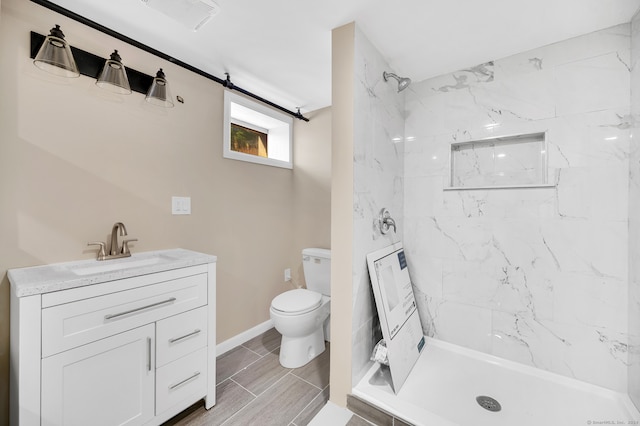 bathroom featuring a tile shower, vanity, and toilet