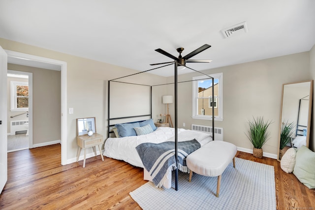 bedroom featuring multiple windows, ceiling fan, radiator heating unit, and wood-type flooring