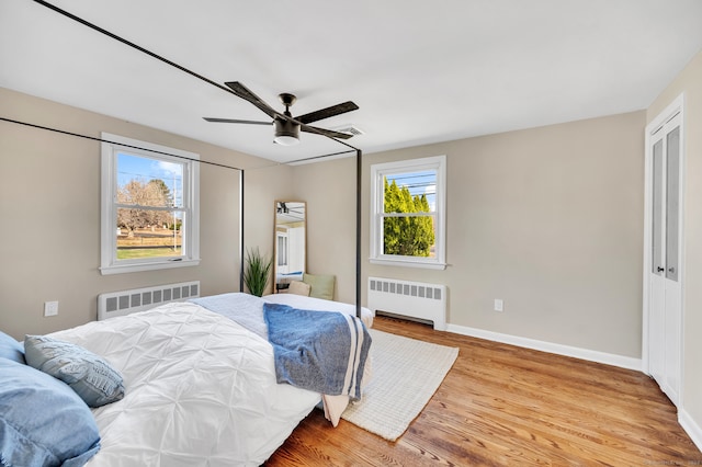 bedroom featuring ceiling fan, radiator heating unit, and multiple windows