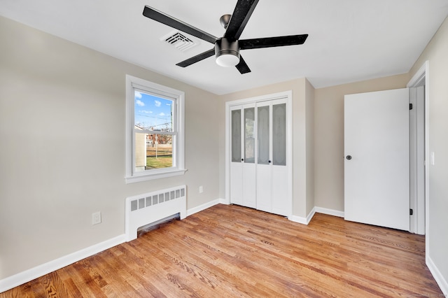 unfurnished room with ceiling fan, radiator heating unit, and light hardwood / wood-style floors