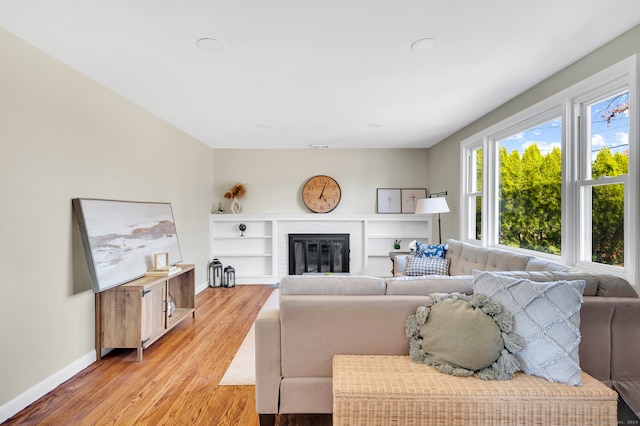 living room featuring light wood-type flooring and a brick fireplace