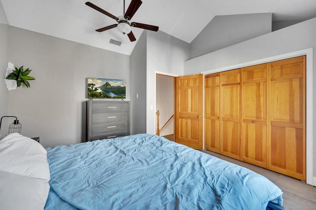 bedroom with a closet, ceiling fan, light hardwood / wood-style flooring, and vaulted ceiling