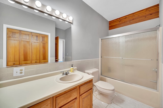 full bathroom featuring combined bath / shower with glass door, vanity, tile patterned floors, and toilet