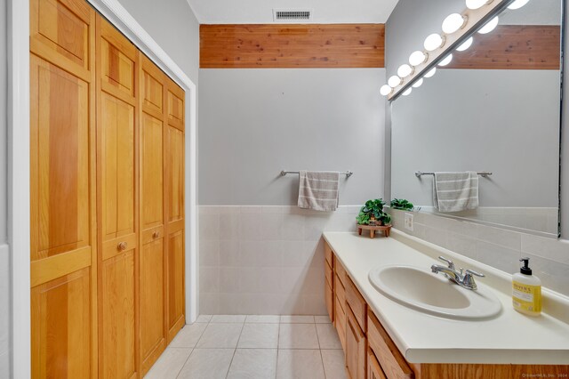 bathroom with tile patterned flooring, vanity, and tile walls