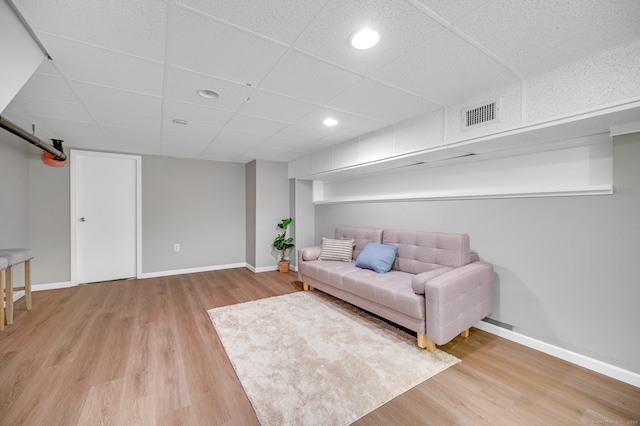 living room with a paneled ceiling and light wood-type flooring