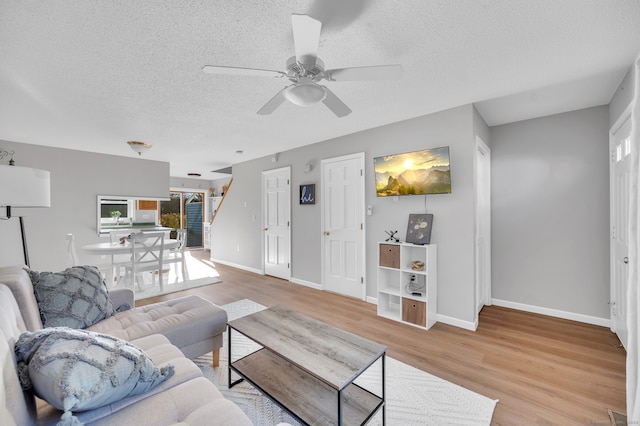 living room with ceiling fan, a textured ceiling, and light hardwood / wood-style flooring