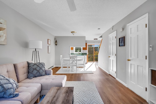 living room featuring baseboard heating, wood-type flooring, and a textured ceiling