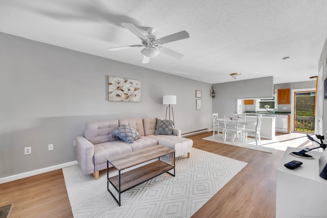 living room with a textured ceiling, a baseboard heating unit, and light wood-type flooring