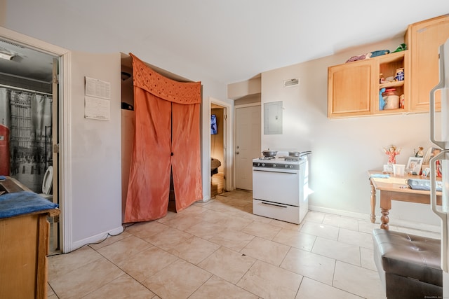 kitchen with electric panel, gas range gas stove, light brown cabinetry, and light tile patterned floors