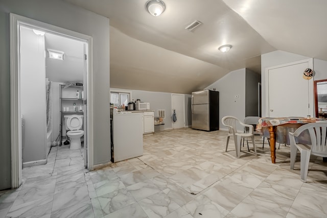 kitchen with white cabinetry, lofted ceiling, and stainless steel refrigerator