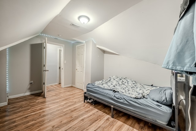 bedroom with hardwood / wood-style floors and vaulted ceiling