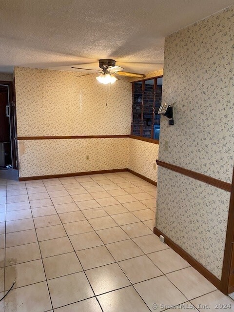 tiled empty room featuring a textured ceiling and ceiling fan