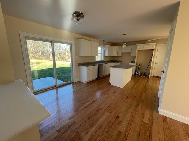 kitchen featuring white cabinets, a kitchen island, light hardwood / wood-style floors, and hanging light fixtures