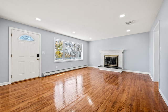 unfurnished living room featuring a brick fireplace, a baseboard radiator, and hardwood / wood-style flooring