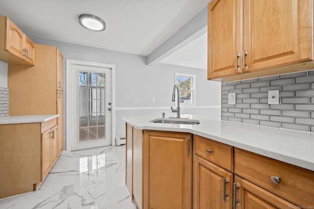 kitchen with kitchen peninsula, baseboard heating, backsplash, and sink