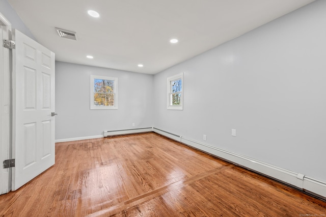 spare room featuring baseboard heating and wood-type flooring