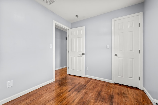 unfurnished bedroom with dark hardwood / wood-style flooring