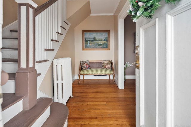 stairway with radiator heating unit, ornamental molding, and hardwood / wood-style flooring