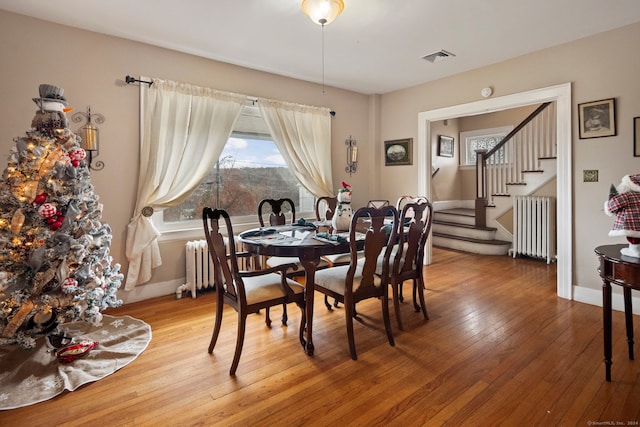 dining area with hardwood / wood-style flooring and radiator