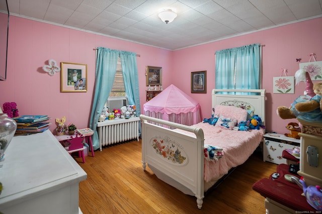 bedroom featuring hardwood / wood-style floors, crown molding, and radiator