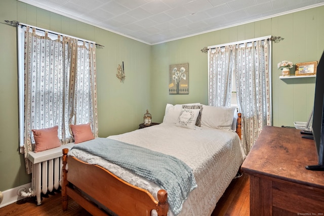 bedroom with dark hardwood / wood-style floors, crown molding, and radiator