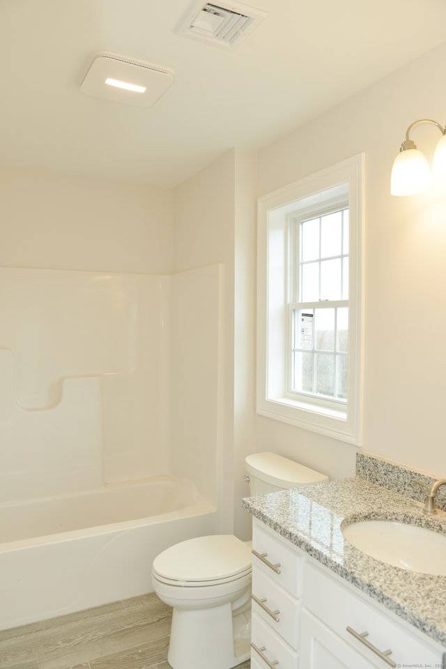 full bathroom with washtub / shower combination, vanity, wood-type flooring, and toilet