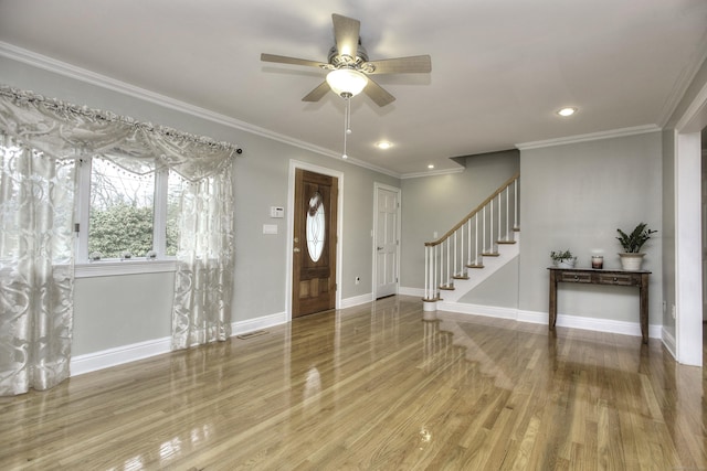 foyer entrance featuring hardwood / wood-style flooring, ceiling fan, and crown molding