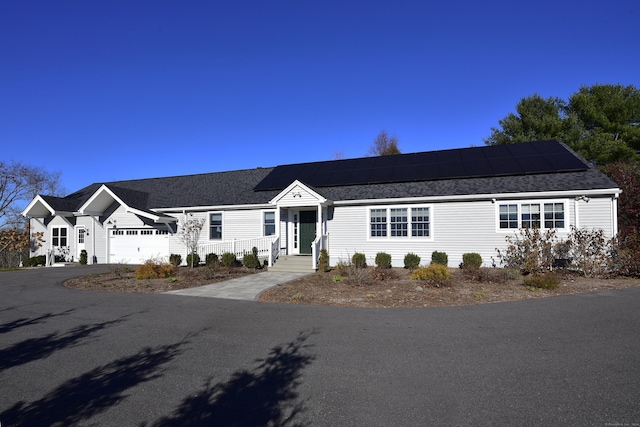 ranch-style home featuring solar panels and a garage