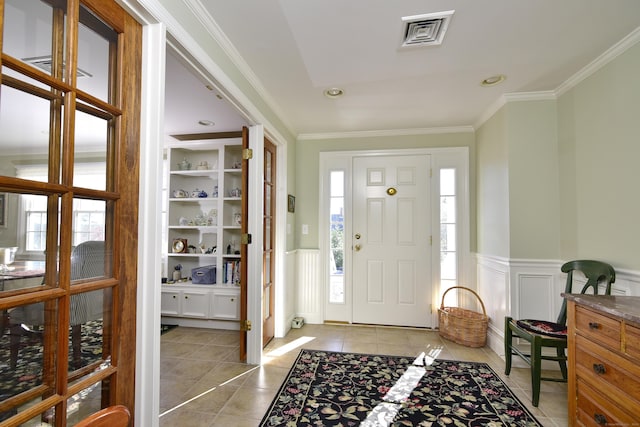 tiled foyer entrance featuring crown molding