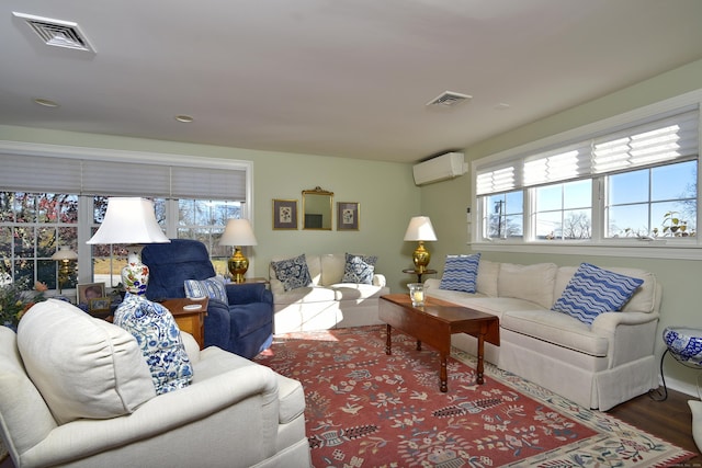 living room featuring a healthy amount of sunlight, wood-type flooring, and a wall unit AC