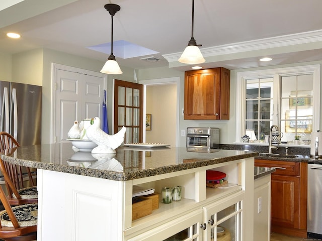 kitchen with appliances with stainless steel finishes, a center island, decorative light fixtures, and sink