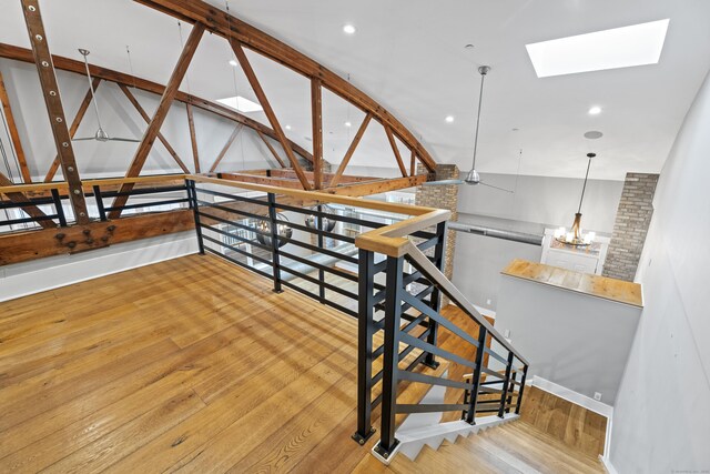 staircase featuring an inviting chandelier, hardwood / wood-style flooring, and lofted ceiling with skylight