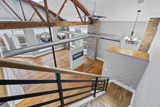 staircase with hardwood / wood-style flooring, ceiling fan with notable chandelier, and high vaulted ceiling