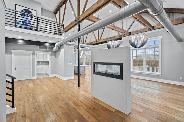 basement featuring a notable chandelier, light hardwood / wood-style flooring, and a multi sided fireplace