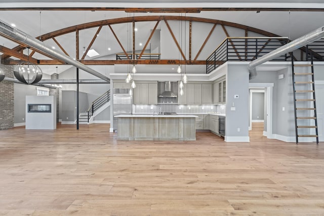 kitchen with wall chimney exhaust hood, a center island, high vaulted ceiling, gray cabinets, and pendant lighting