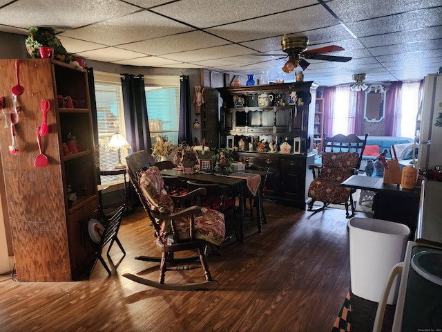 dining room featuring ceiling fan, a drop ceiling, and hardwood / wood-style flooring