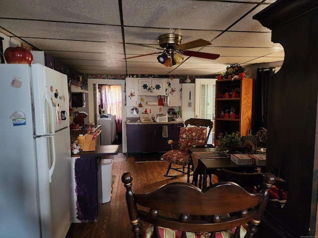 dining space with a paneled ceiling, ceiling fan, washer and dryer, and dark wood-type flooring