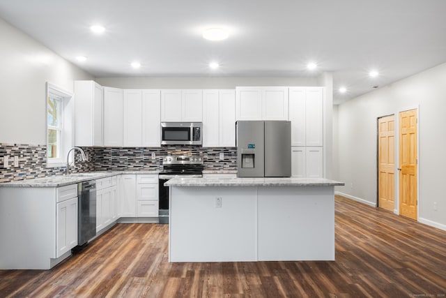 kitchen with stainless steel appliances, sink, white cabinetry, dark hardwood / wood-style floors, and a kitchen island