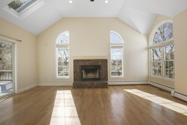 unfurnished living room featuring hardwood / wood-style flooring, a high end fireplace, lofted ceiling with skylight, and ceiling fan