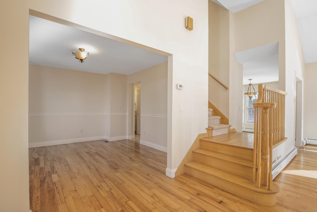 stairway with hardwood / wood-style floors and a baseboard heating unit