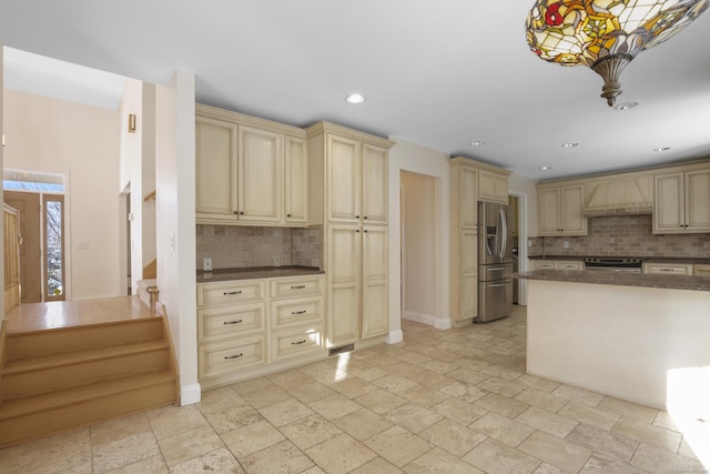 kitchen with stainless steel fridge, custom exhaust hood, cream cabinetry, tasteful backsplash, and oven